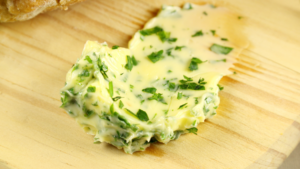 masłem czosnkowym i posiekanymi ziołami na drewnianej desce